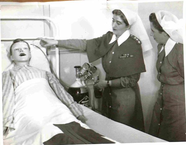 1955 RAANC Course, School of Army Health, Healesville. Sister Instructor Captain D G M Potter of Guildford, WA demonstrates the correct method of administering oxygen to the patient to student WO11 M Trotter of Sydney, NSW.